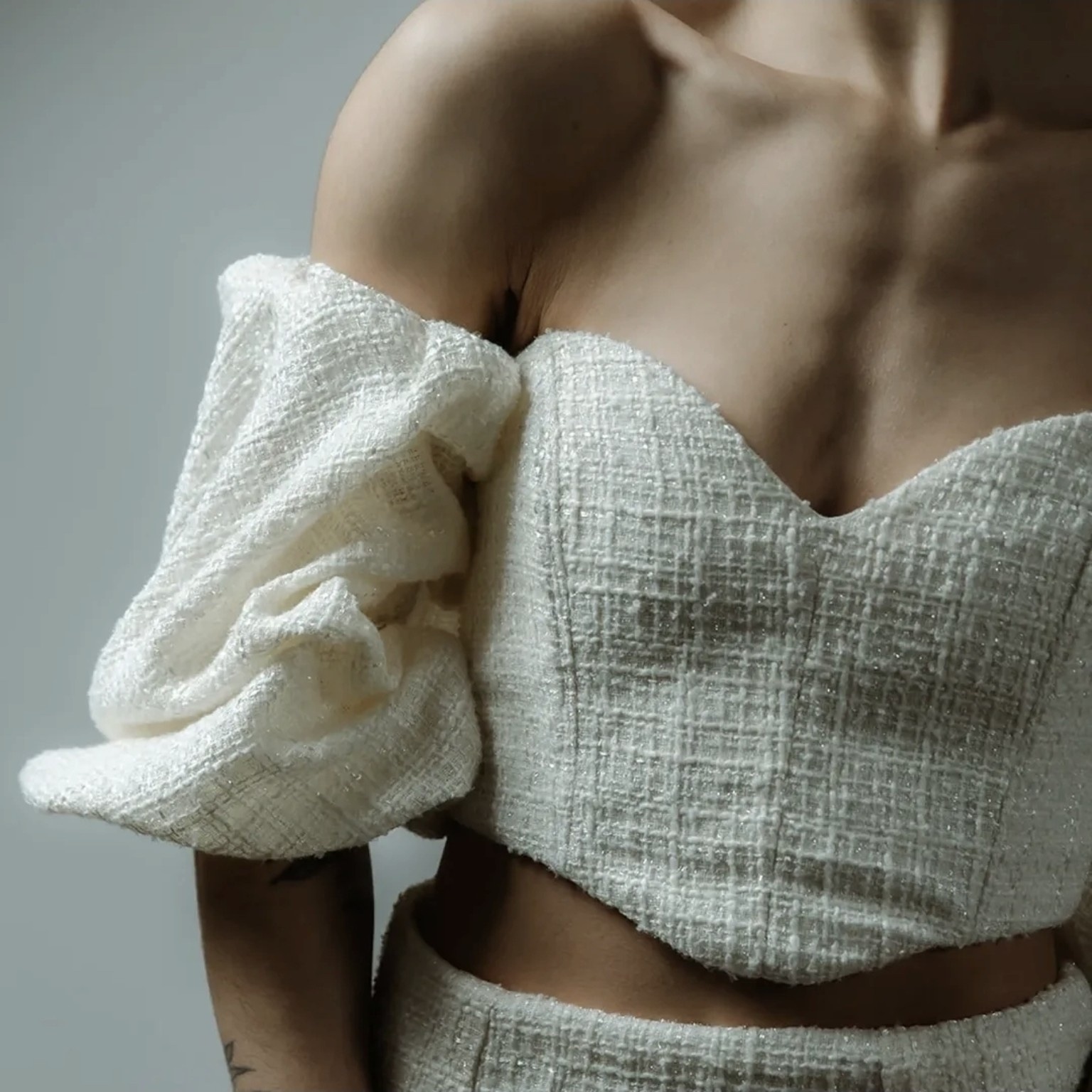 Close detail of a textured bridal corset top with dramatic puff sleeve